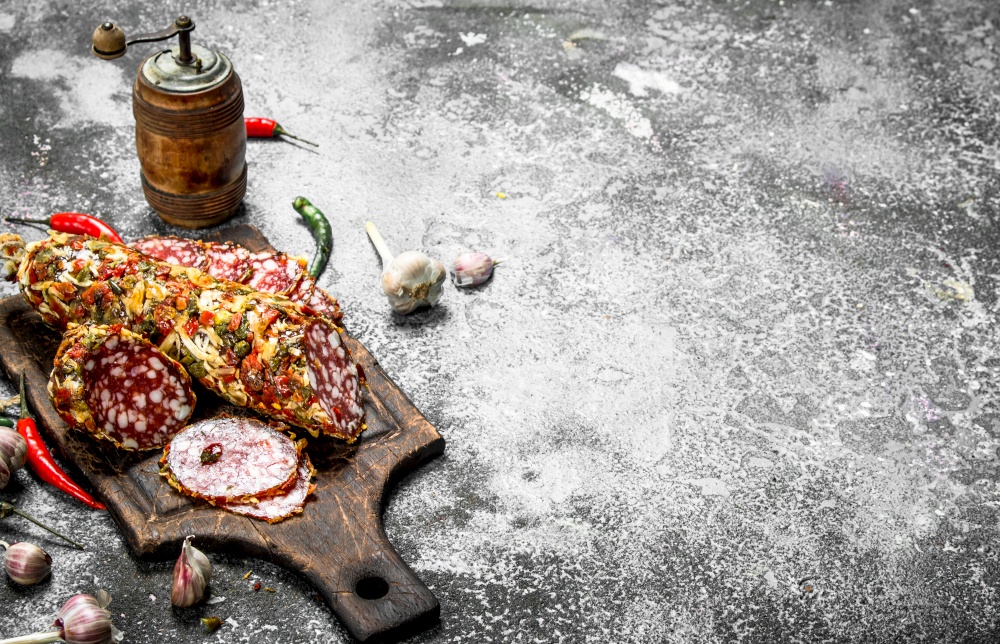 Salami with spices and herbs. On a rustic background.. Salami with spices and herbs.
