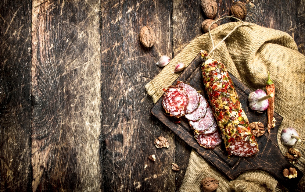 Salami with garlic and nuts. On a wooden background.. Salami with garlic and nuts.