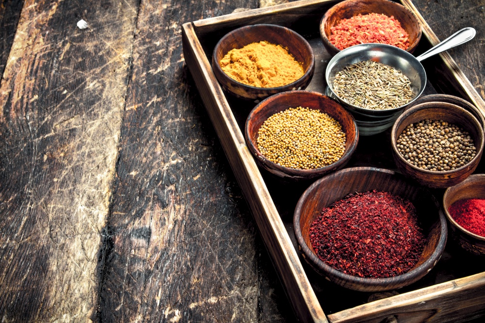 Various ground spices and herbs in an old tray. On a wooden background.. Various ground spices and herbs in an old tray.