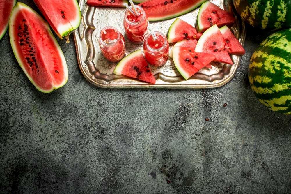 Watermelon juice in bottles on a steel tray. On a rustic background.. Watermelon juice in bottles on a steel tray.