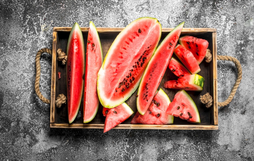 Sliced ripe watermelon on a wooden tray. On a rustic background.. Sliced ripe watermelon on a wooden tray.