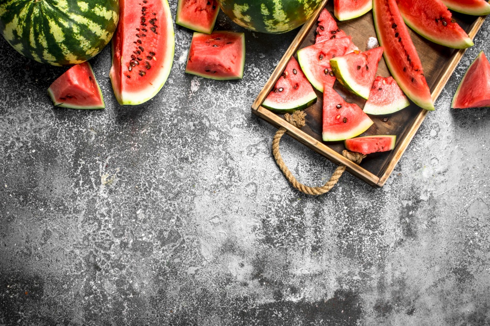Sliced ripe watermelon on a wooden tray. On a rustic background.. Sliced ripe watermelon on a wooden tray.