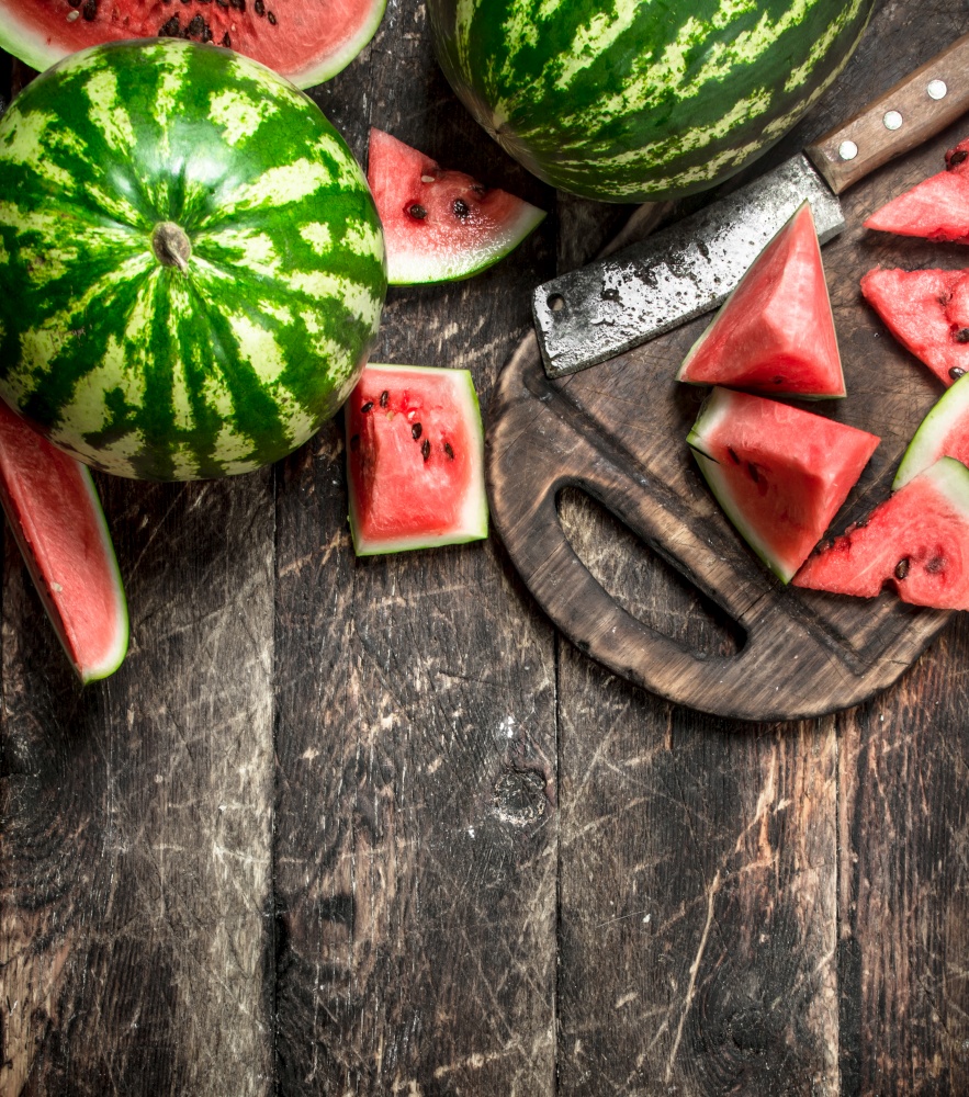 Sliced slices of ripe watermelon on a board. On a wooden background.. Sliced slices of ripe watermelon on a board.