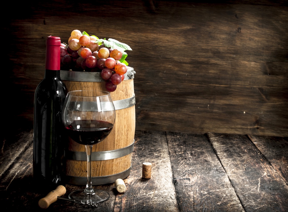 barrel of red wine with grapes and a corkscrew. On a wooden background.. barrel of red wine with grapes and a corkscrew.
