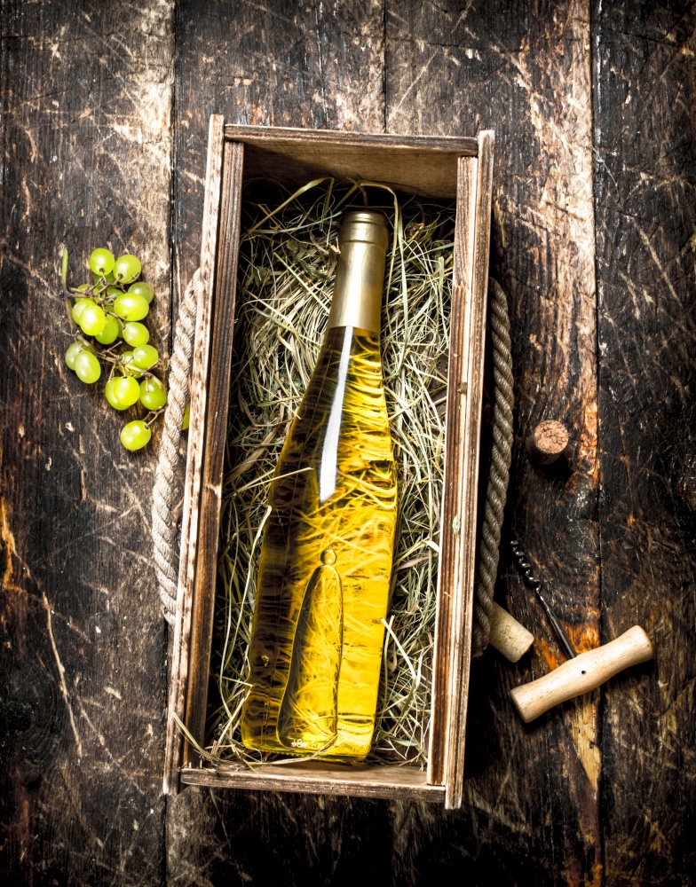 bottle of white wine in an old box. On a wooden background.. bottle of white wine in an old box.