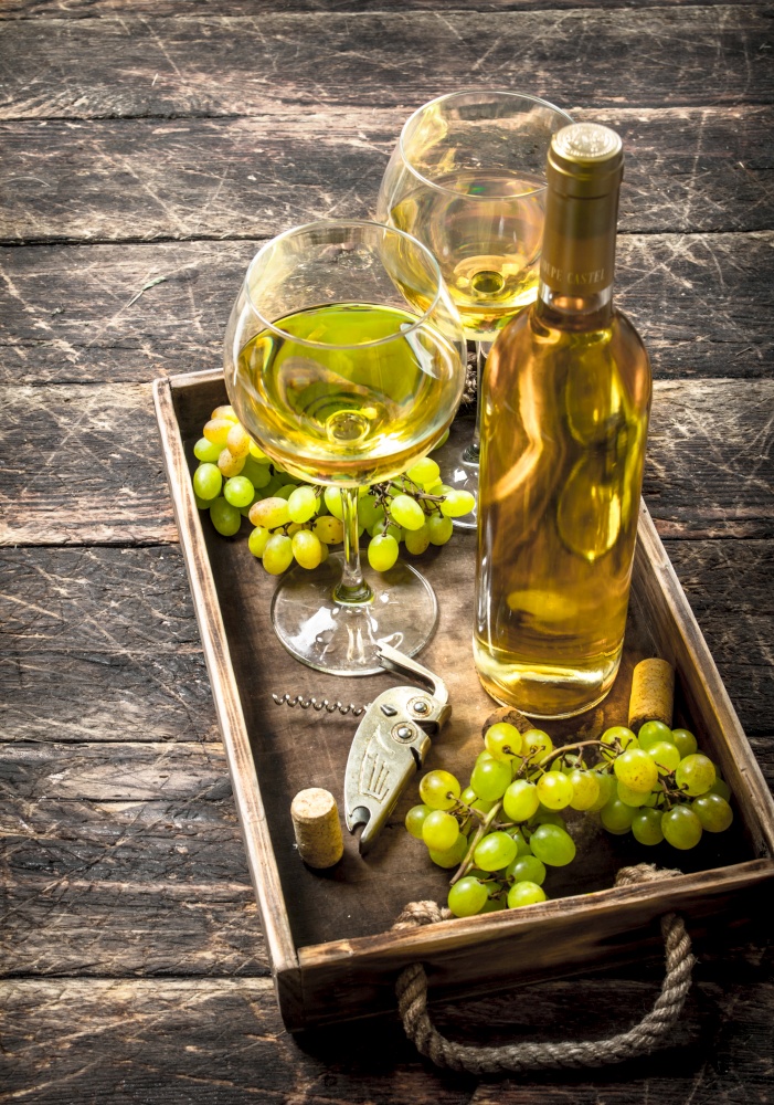 White wine with fresh grapes on an old tray. On a wooden background.. White wine with fresh grapes on an old tray.