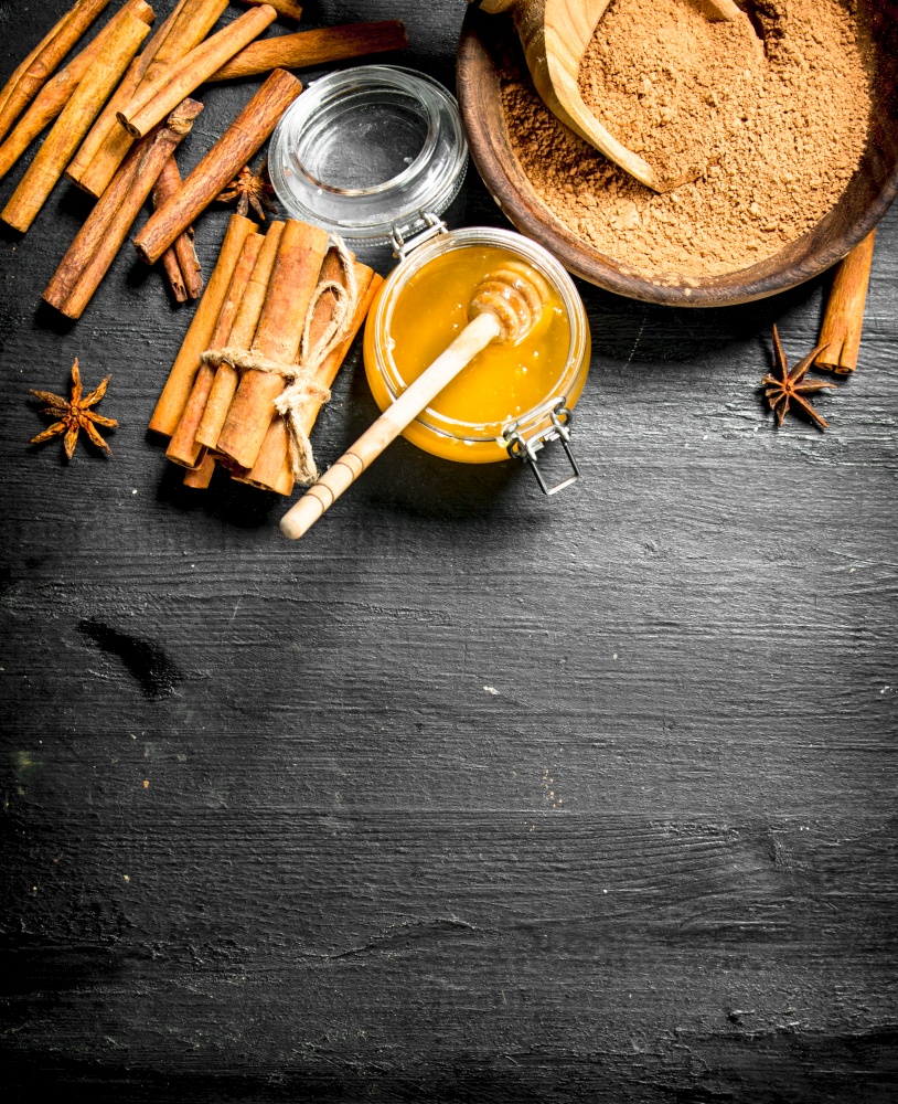 Fresh honey with ground cinnamon . On a black wooden table.. Fresh honey with ground cinnamon .