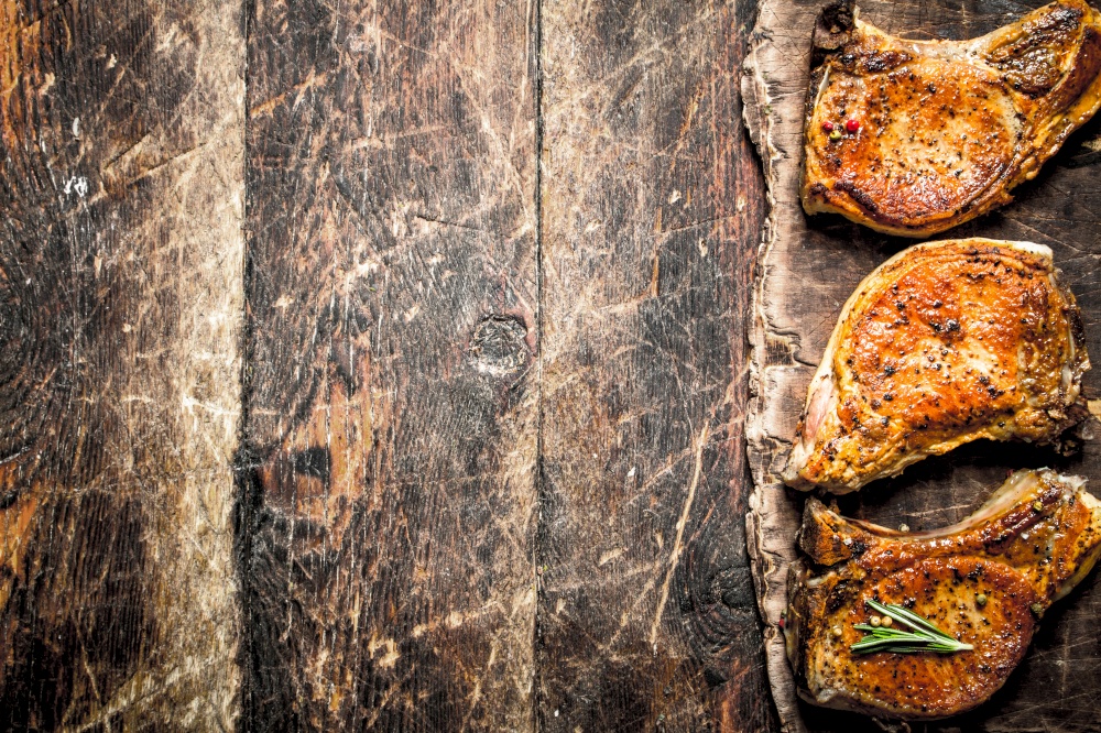 Grilled pork steak with spices. On wooden background.. Grilled pork steak with spices.