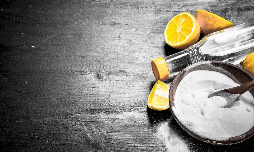 Baking soda in a bowl with vinegar and lemon slices. On the black chalkboard.. Baking soda in a bowl with vinegar and lemon slices.