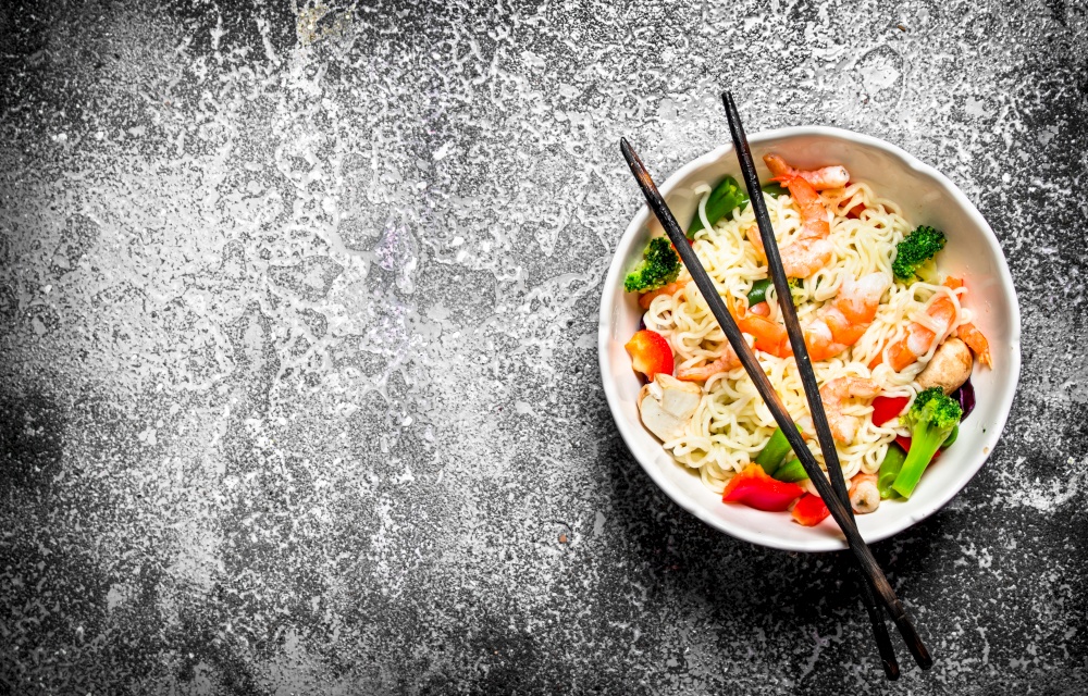 Asian food. Chinese noodles with vegetables in a bowl . On an old rustic background .. Asian food. Chinese noodles with vegetables in a bowl .