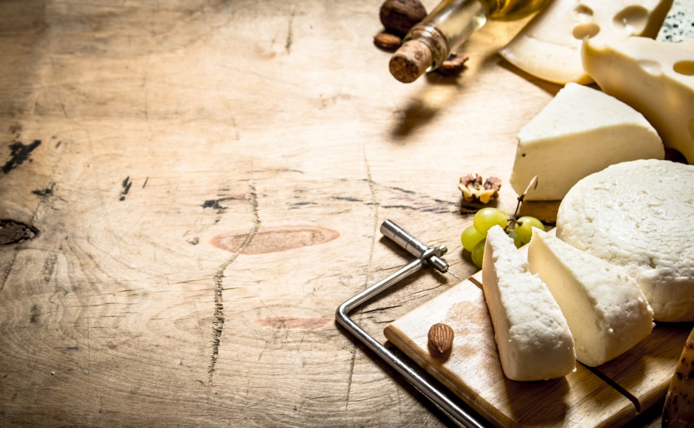 White wine with different types of cheese. On a wooden table.. White wine with different types of cheese.