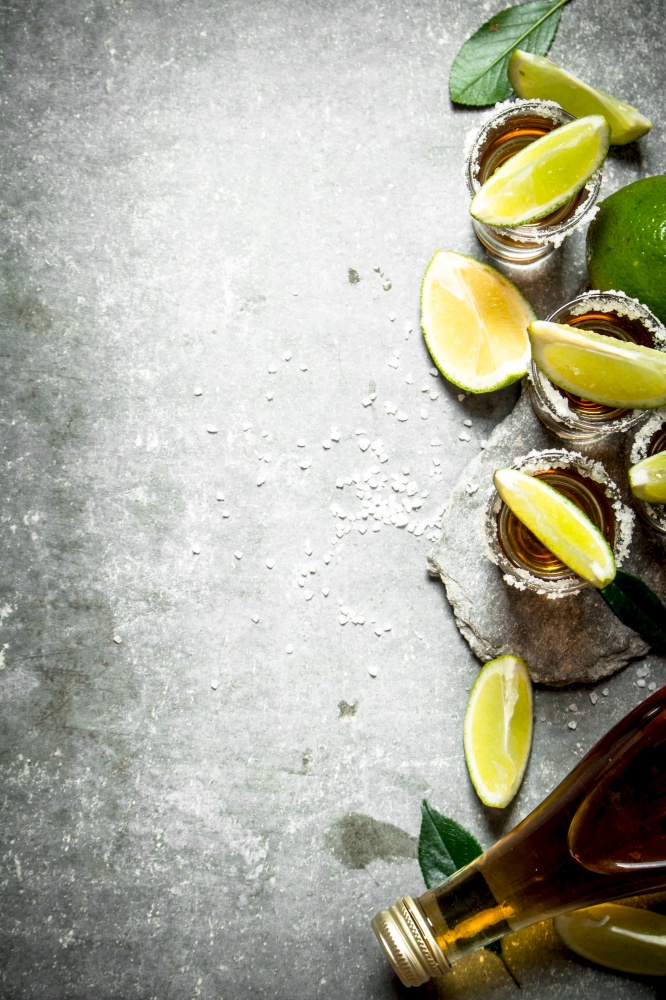 Tequila with salt and lime slices. On the stone table.. Tequila with salt and lime slices.