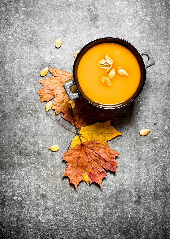 Autumn style. Pumpkin soup from a ripe pumpkin. On the stone table.. Pumpkin soup