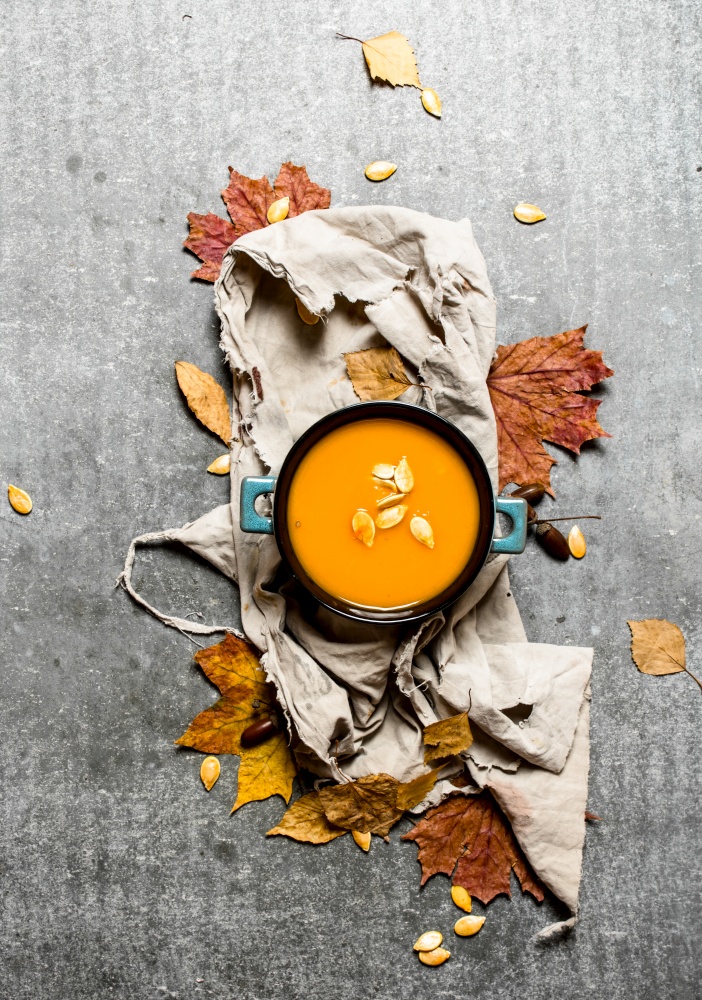 Autumn style. Pumpkin soup from a ripe pumpkin. On the stone table.. Pumpkin soup