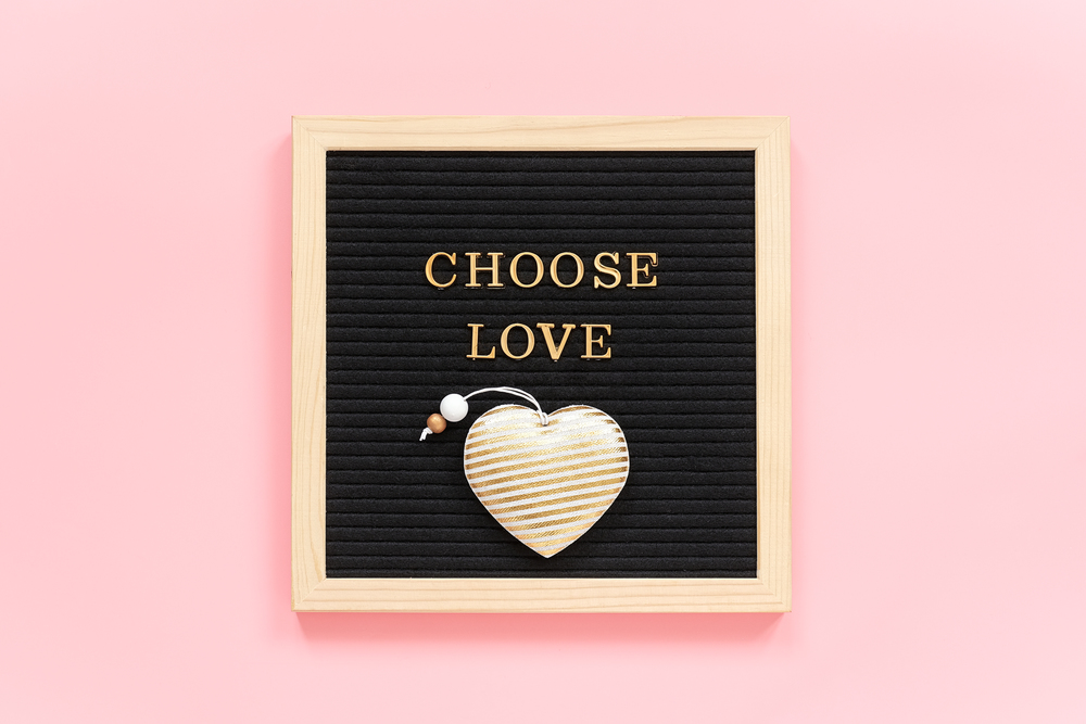 Choose love. Motivational quote in gold letters and textile heart on black letter board on pink background. Concept inspirational quote of the day. Template for Valentine card, postcard. Top view.. Choose love. Motivational quote in gold letters and textile heart on black letter board on pink background. Concept inspirational quote of the day. Template for Valentine card, postcard. Top view