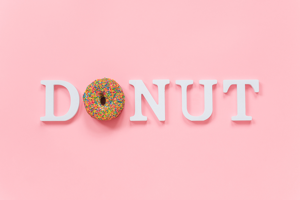 Multi colored glazed donut and white letters Donut on pink background. Top view Flat lay .. Multi colored glazed donut and white letters Donut on pink background. Top view Flat lay