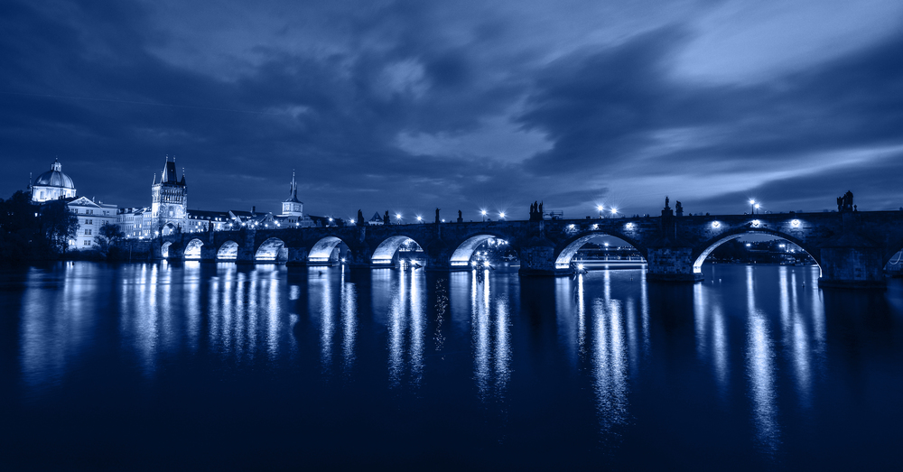 Beautiful night view of Charles Bridge and Vltava river, Prague, Czech Republic. Charles Bridge and Vltava river with night lights. Trendy banner toned in classic blue - color of the 2020 year. Beautiful night view of Charles Bridge and Vltava river, Prague, Czech Republic.