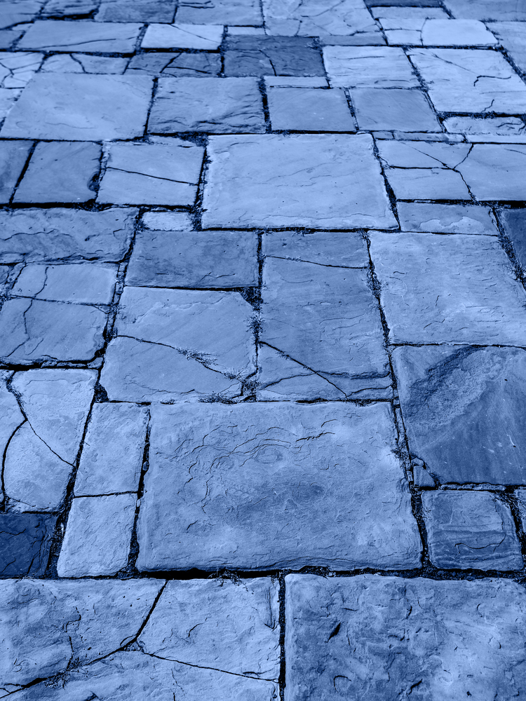 Light brown ancient stone road close up. Old pavement of granite. Brown cobblestone sidewalk. Mock up or vintage grunge texture. Trendy banner toned in classic blue - color of the 2020 year. Light brown ancient stone road close up. Old pavement of granite. Brown cobblestone sidewalk.