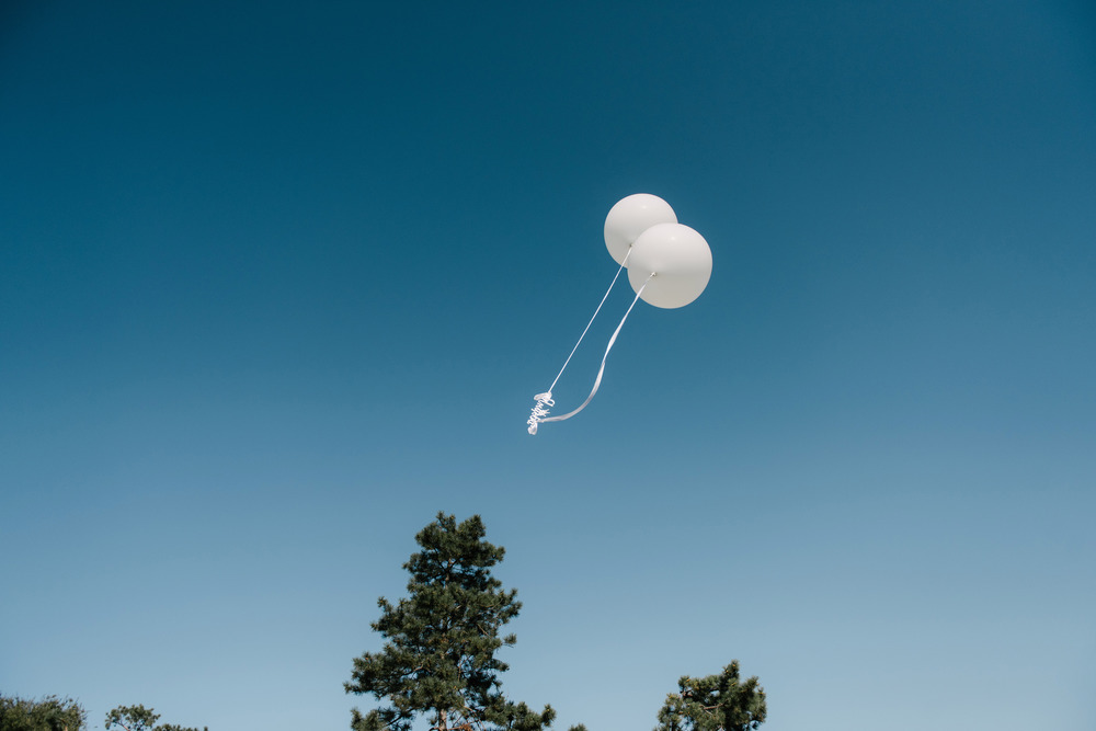 White balloons fly away. White balloons released into the sky. White balloons against the blue sky. White balloons fly away. White balloons released into the sky.