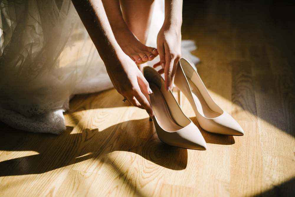 Bride in a wedding dress puts shoes on her feet on the wedding day. Bride in a wedding dress puts shoes on her feet