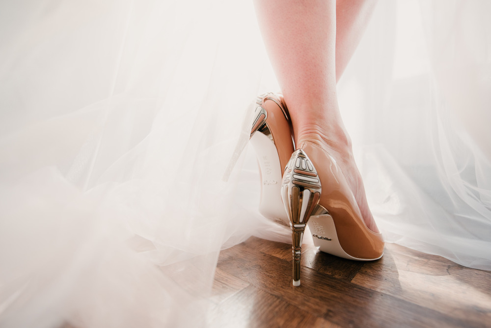 The legs of the bride in a wedding dress in shoes close op. The legs of the bride in a wedding dress in shoes