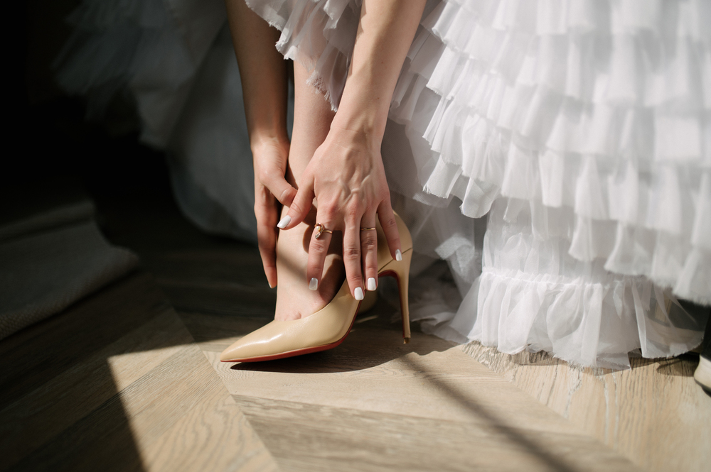 Bride in a wedding dress puts shoes on her feet on the wedding day. Bride in a wedding dress puts shoes on her feet