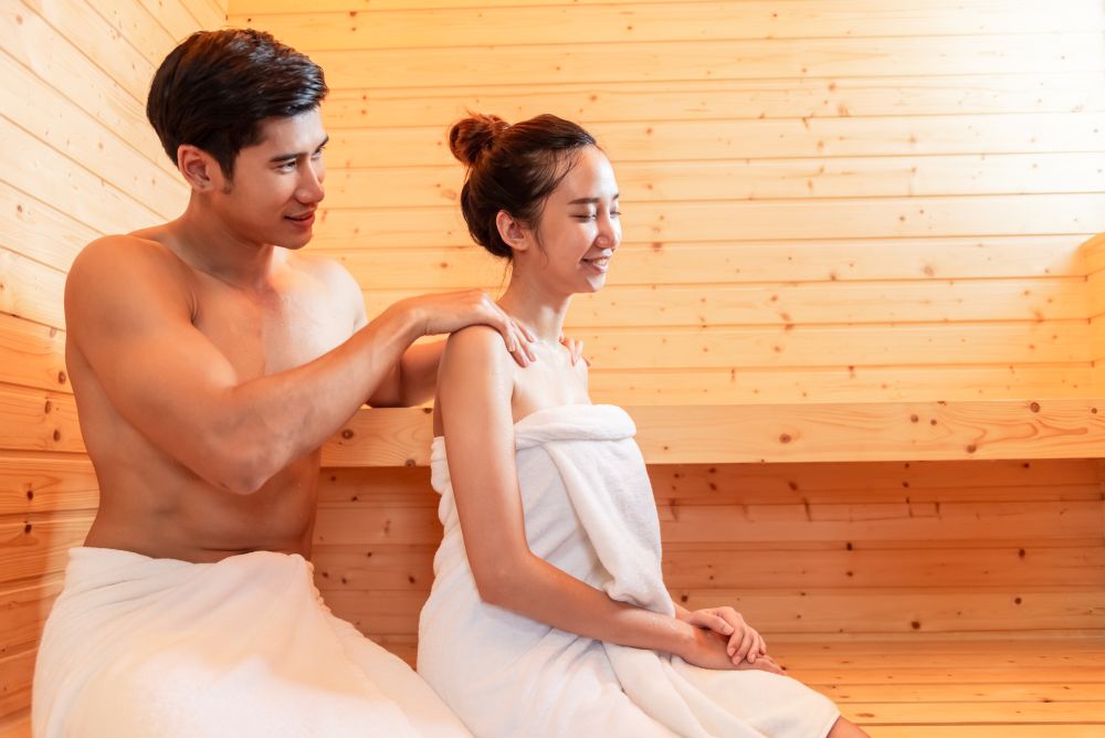 Young Asian couples have romantic relaxing massage in sauna room. Skin care heat treatment and body clean up and refreshing in spa steam bath. Healthy and Honeymoon concept. Happiness valentines day