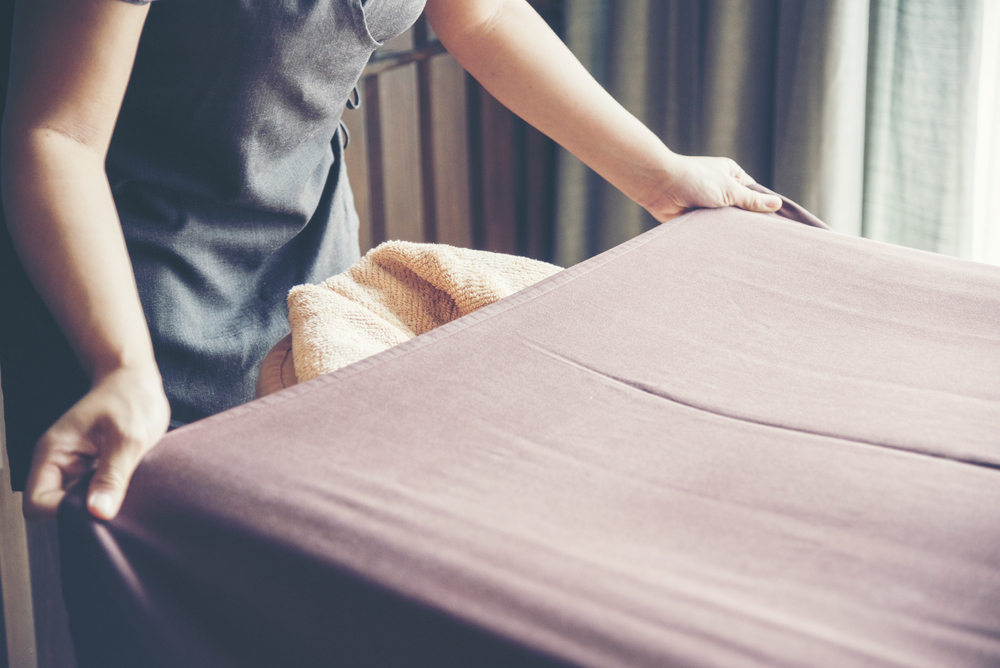 House Cleaner prepare bed sheet in  Luxury Hotel. Chambermaid housework laundry make bed sheet.
