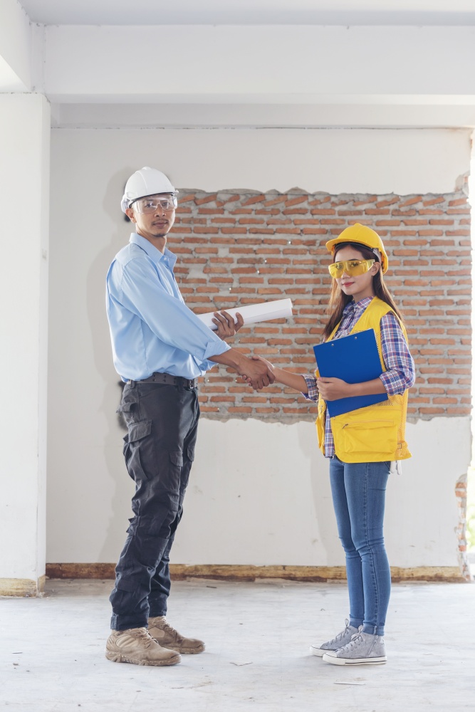 Civil Construction engineer teams shaking hands together wear work helmets worker on construction site. Foreman industry project working engineer teamwork. Two asian engineer team shake hands together