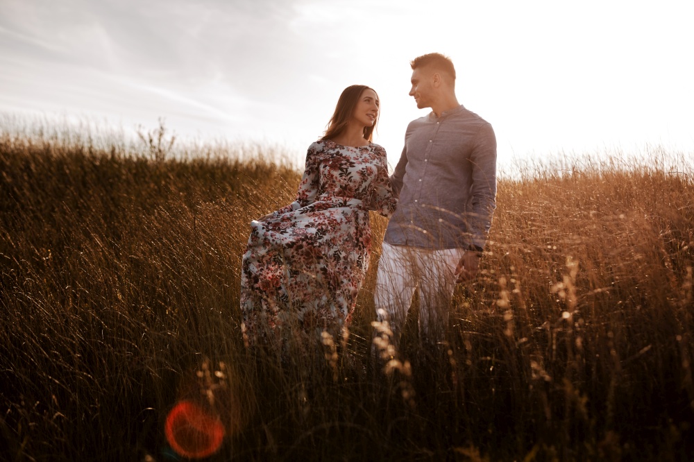 young couple resting in nature in a field. couple at sunset.. young couple resting in nature in a field. couple at sunset