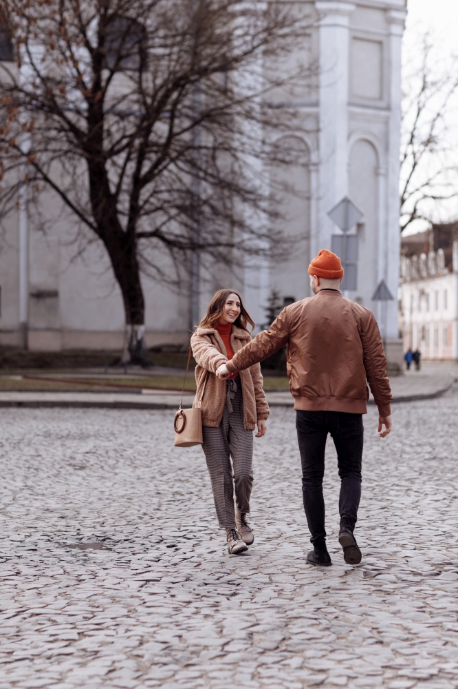 beautiful cheerful couple running around the city. Lifestyle photo a couple holding hands. Happy lucky couple have fun on the walk, run and smile. happy together