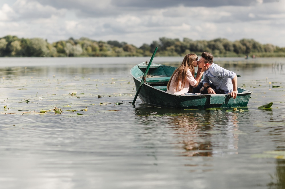 Just relaxing. Beautiful young couple enjoying romantic date while rowing a boat. Just relaxing. Beautiful young couple enjoying romantic date while rowing a boat. Loving couple resting on a lake while riding a green boat. romance.