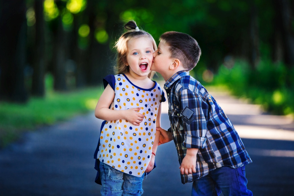 Children&rsquo;s love, a little boy and a girl, having fun, laugh and smile, and kiss outdoors.. Children&rsquo;s love, a little boy and a girl, having fun, laugh and smile, and kiss outdoors