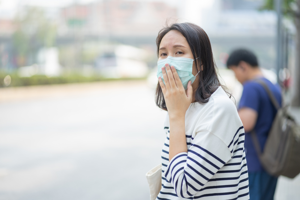 Woman wearing face mask protect filter against air pollution (PM2.5) or wear N95 mask. protect pollution, anti smog and Covid 19 viruses, Air pollution health problem. environmental pollution concept.