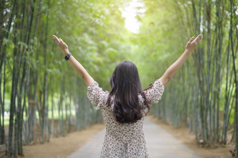 a young woman is open arms in the green nature background. . young woman is open arms in the green nature background.