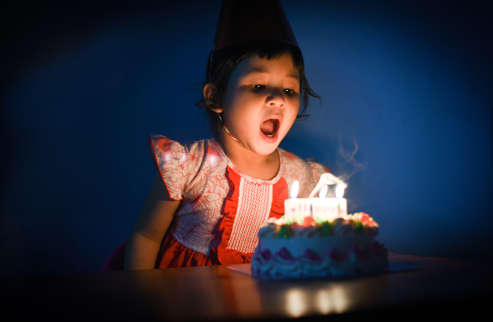 Asia child blowing out candles on birthday cake / Portrait of little pretty girl Happy Birthday Party at night