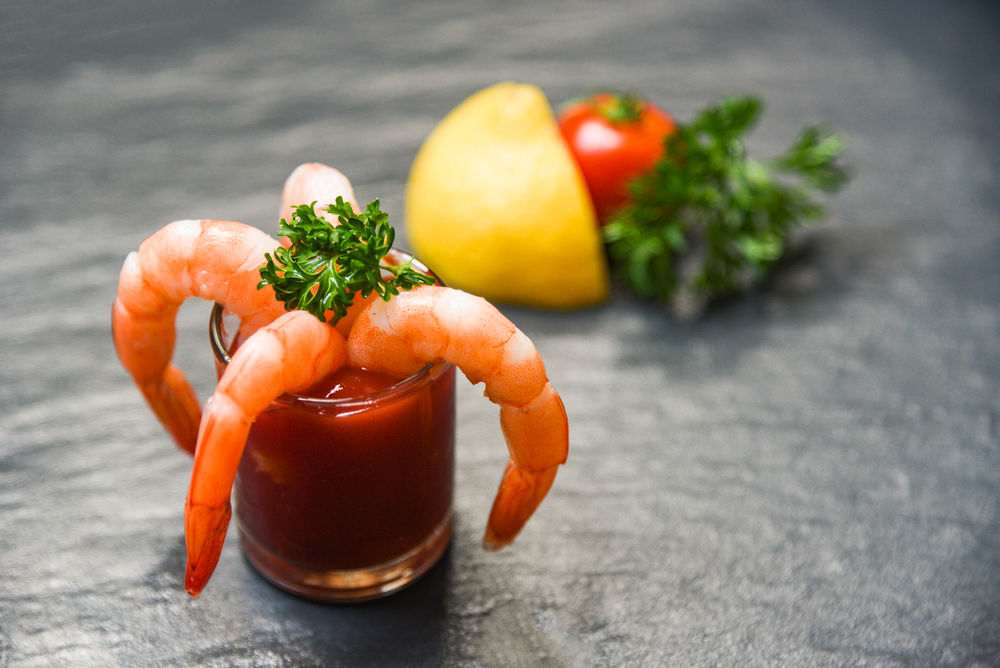 Glass shrimp cocktail in tomato sauce / Shellfish seafood boiled Shrimps prawns ketchup ocean gourmet dinner and tomato lemon spices on dark background