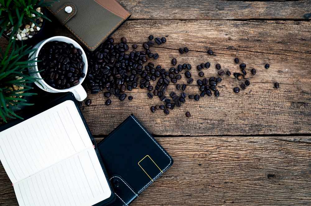 notebook and a mug of coffee beans on the table top view
