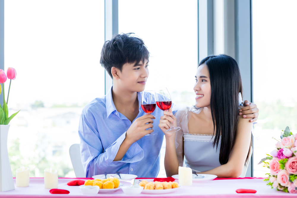 Valentine&rsquo;s day concept,Happy Asian Young sweet couple having romantic the Lunch with clinking toasting wine glasses at the restaurant background.