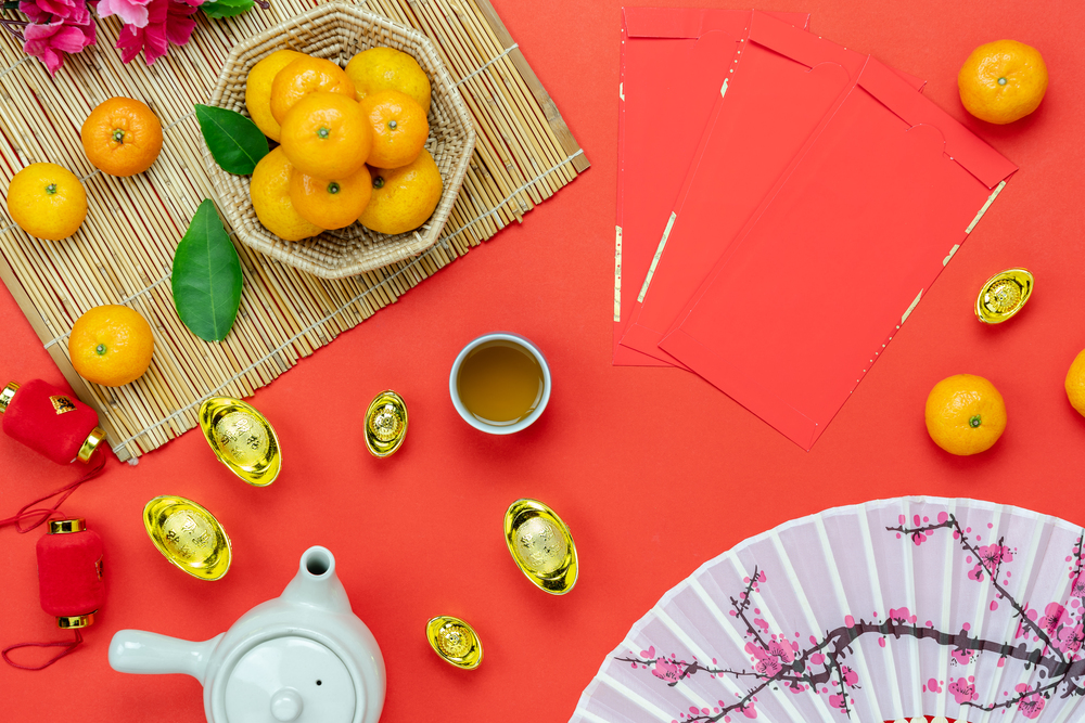 Chinese language mean rich or wealthy and happy.Table top view Lunar New Year & Chinese New Year vacation concept background.Flat lay orange in wood basket & cup of tea on modern rustic red backdrop.
