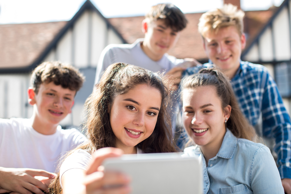 Group Of Teenagers Taking Selfie On Mobile Phone Outdoors