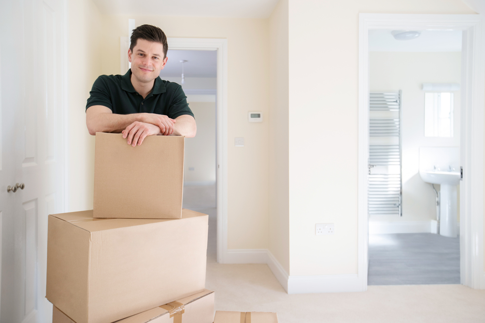 Portrait Of Removal Man Carrying Boxes Into New Home On Moving Day