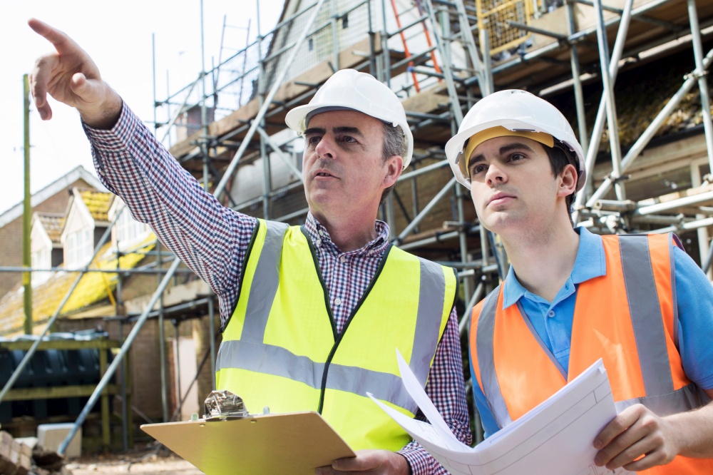 Architect On Site Discussing Plans With Builder