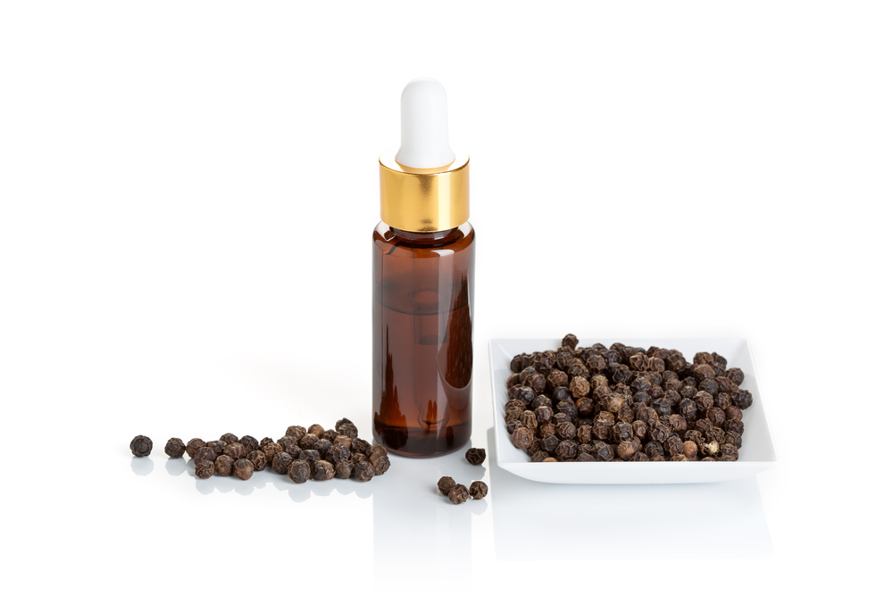 Black pepper essential oil isolated on white background. Black pepper oil glass bottle with dropper for beauty, skin care, wellness and medicinal purposes. Piper nigrum oil