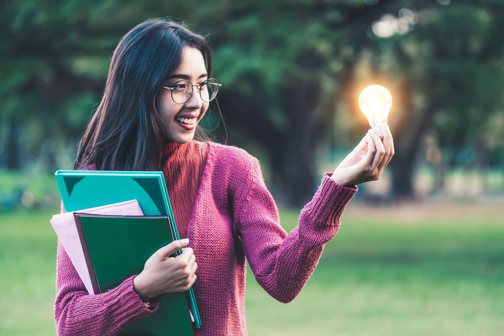 Creative young woman hold shinning light bulb. Concept of knowledge, intelligence and inspiration.