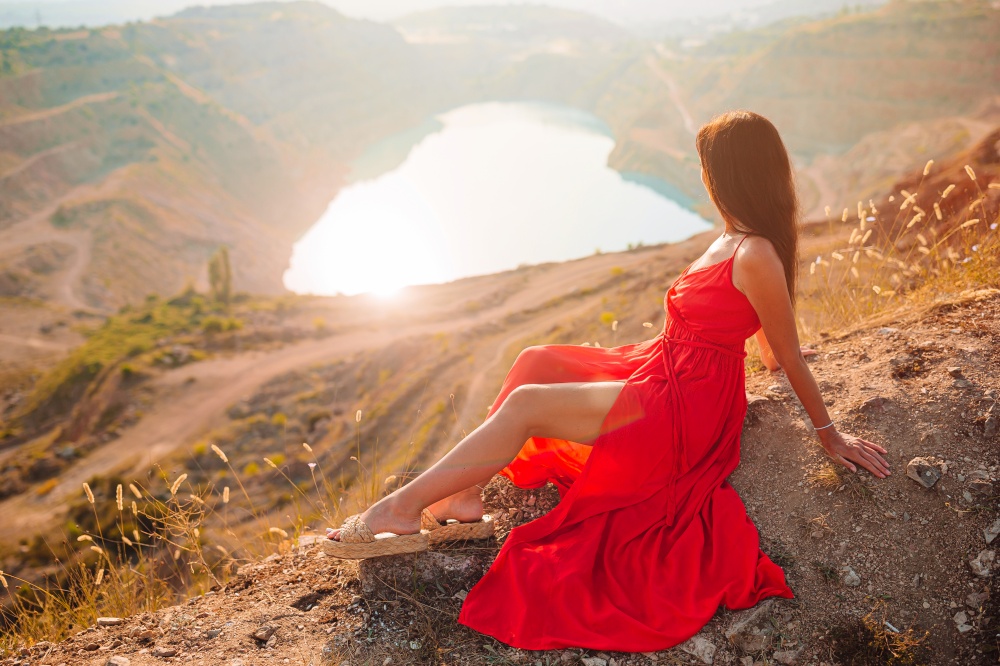Woman in red dress standing near the lake like heart. Concept of european vacation. Beautiful landscape. Mother near the lake at the day time.