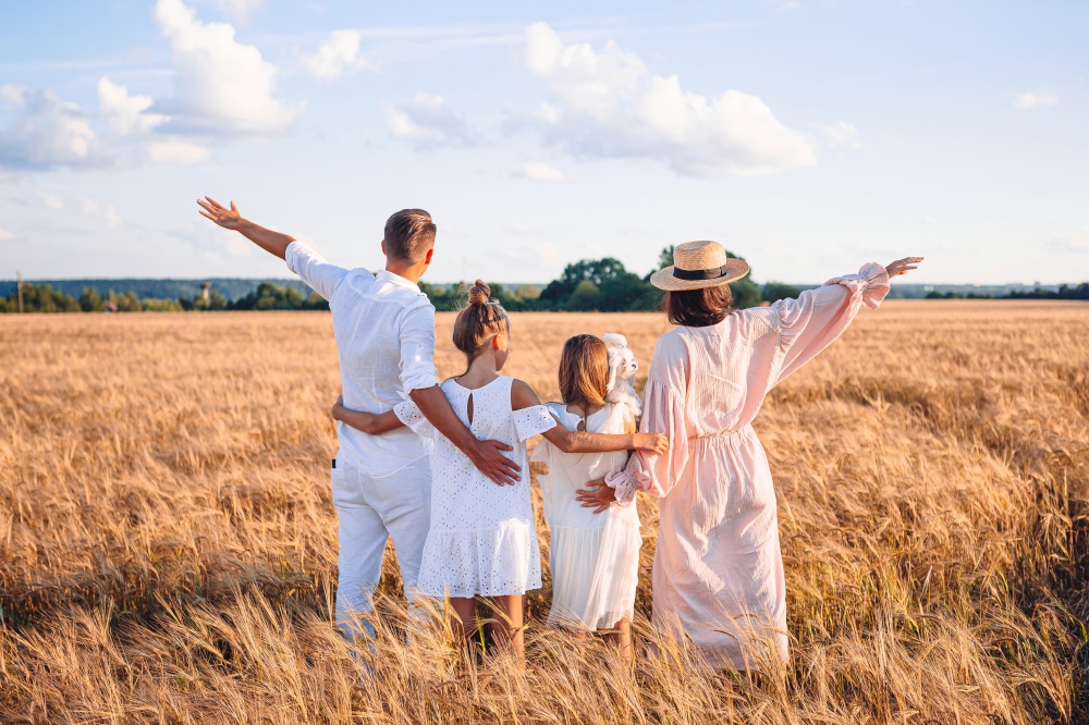 Happy family in a wheat field. Parents and kids playing on summer meadow. Happy family playing in a wheat field