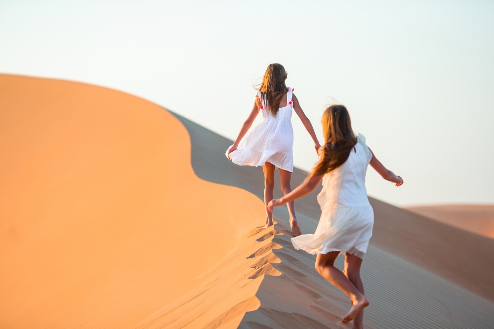 Little girls on vacation at dunes in desert. Girls among dunes in Rub al-Khali desert in United Arab Emirates