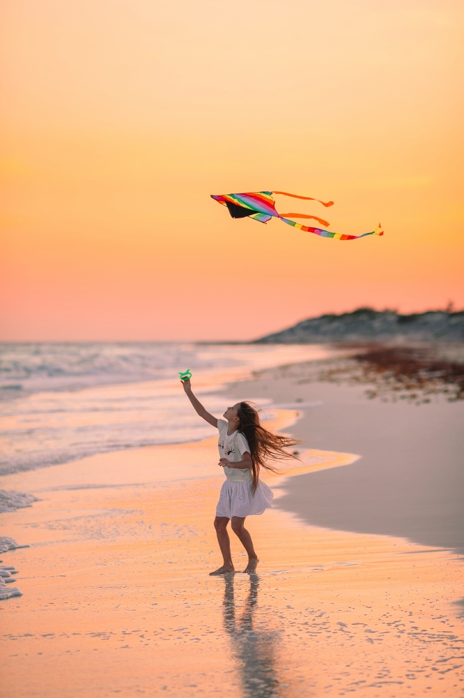 Adorable happy little girl on the beach at sunset. Adorable happy little girl on white beach at sunset.
