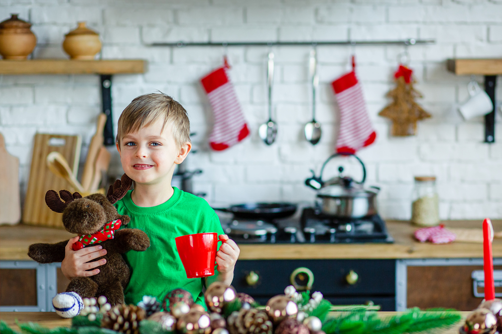 Good morning. A little boy drinks tea at the kitchen table and hugs a teddy moose. A time of miracles and fulfillment of desires. Merry Christmas.. Good morning. A little boy drinks tea at the kitchen table and hugs a teddy moose. A time of miracles and fulfillment of desires.